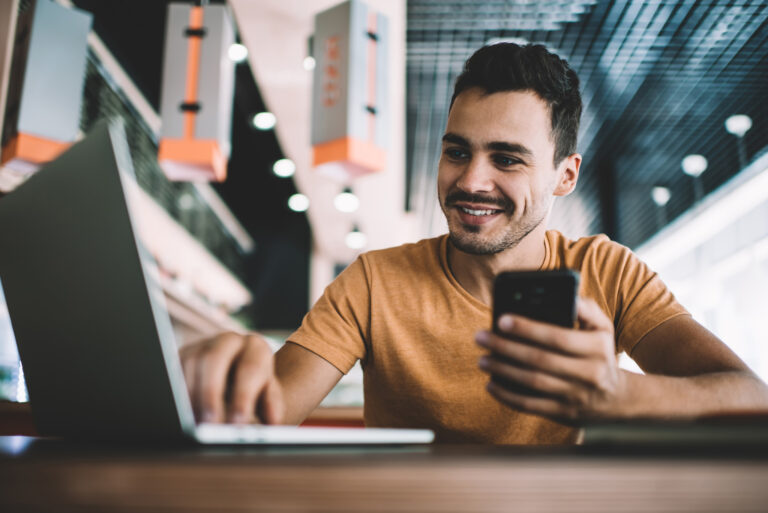 Close up of a man smiling at a laptop.